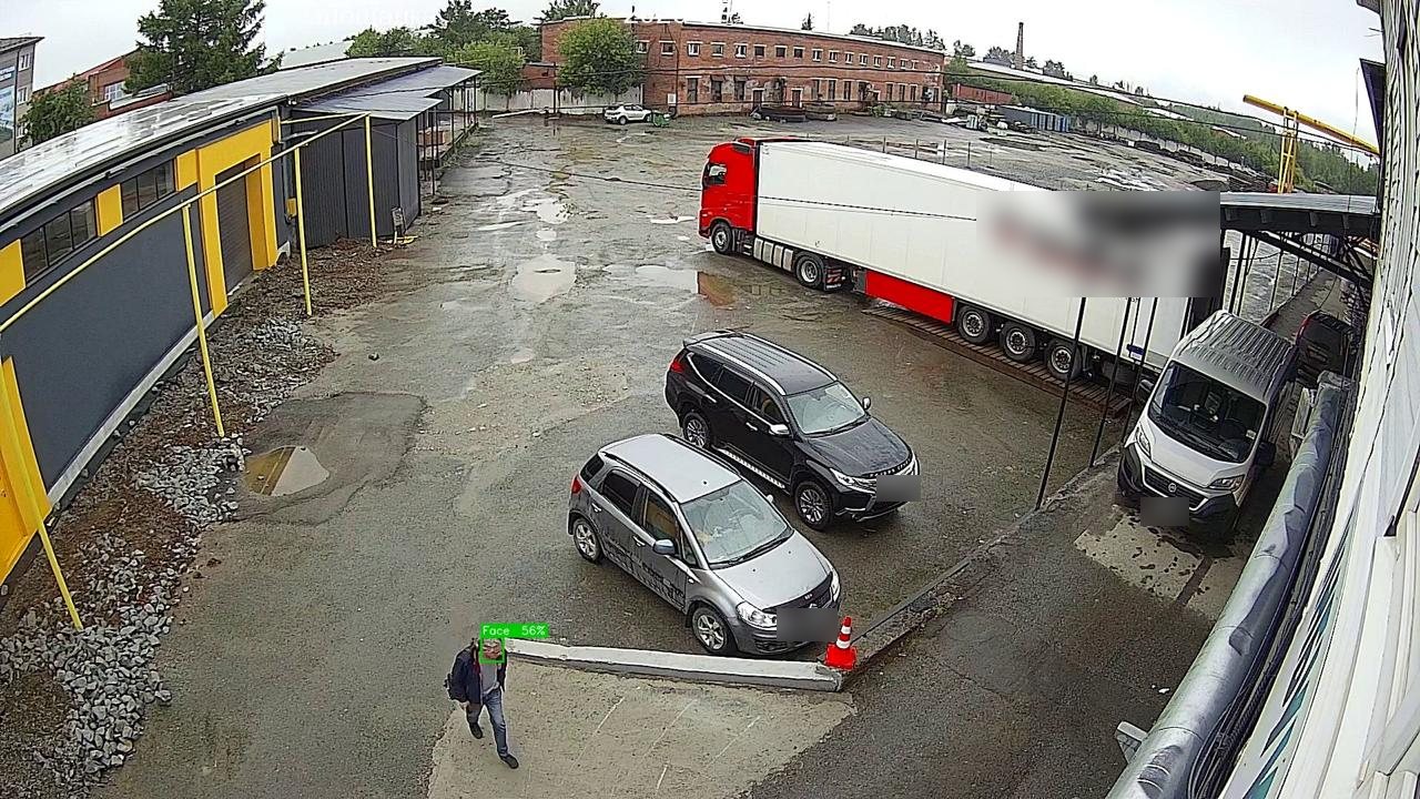 Real camera frame: a truck yard with a person walking in, face detected (face blurred)
